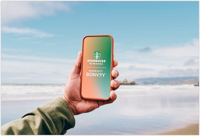 A mobile device with Starbucks Rewards and Marriott Bonvoy logos on the screen.