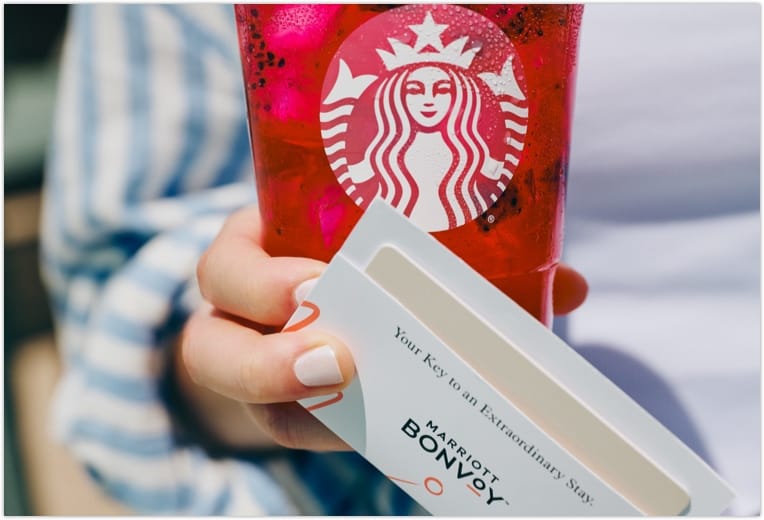 A closeup of someone holding a Marriott Bonvoy key card and Starbucks beverage.
